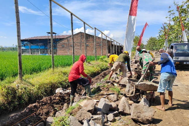 Satgas TMMD Kodim Sragen membangun talud sepanjang 150 meter di Desa Puro untuk mencegah longsor dan menjaga kestabilan jalan cor desa.