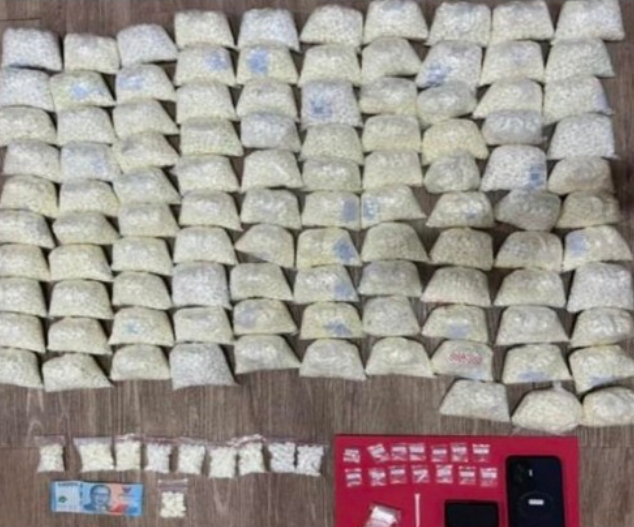 Petugas Polres Pasuruan mengamankan tersangka dan ratusan ribu butir pil double L hasil penggerebekan di Sukorejo.
