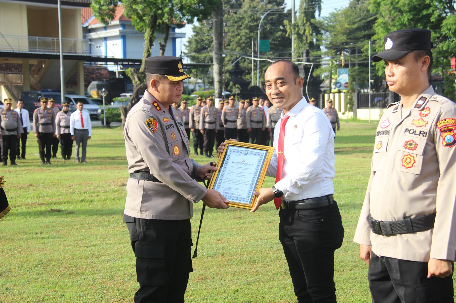 Kapolres Bondowoso menyerahkan penghargaan kepada personel berprestasi di halaman Mapolres.