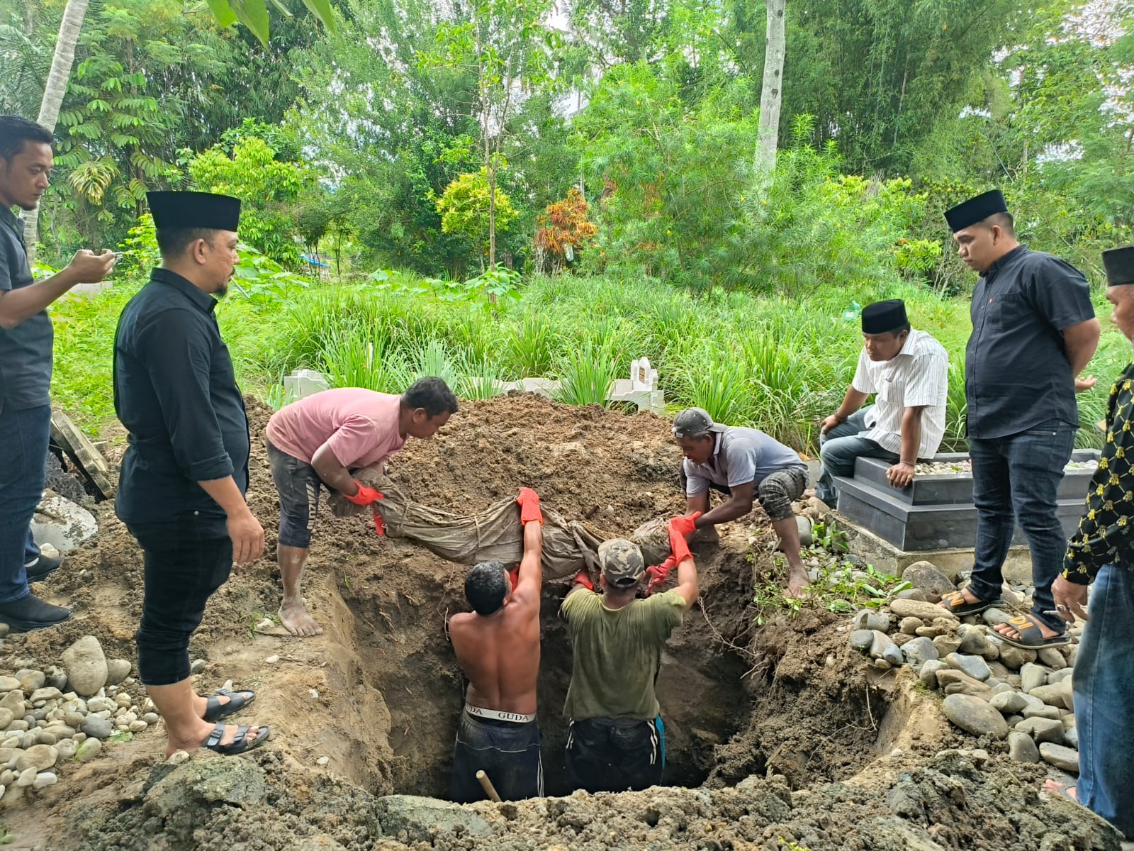 Proses pemindahan makam pasangan suami istri di Madina akibat sengketa warisan keluarga yang disaksikan perangkat desa dan warga setempat.