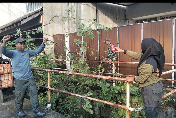 Babinsa Serengan Serda Djoko Riyadi bersama Linmas melakukan kerja bakti membersihkan Sungai Yos Sudarso untuk mencegah banjir.